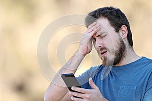 Worried man complaining looking at phone