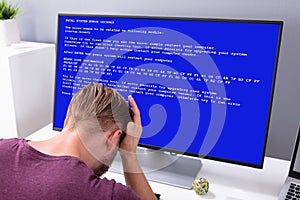 Worried Man At Computer With System Failure On The Screen