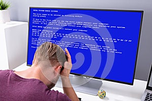 Worried Man At Computer With System Failure On The Screen