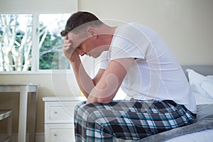 Worried man having a headache in bedroom