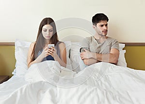 Worried man by his wife smartphone addiction