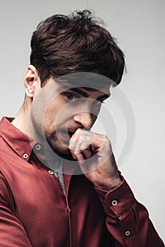 Worried man holding hand near face isolated on grey