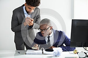 Worried Man Looking At Auditor Analyzing Bill