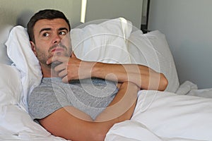 Worried man overthinking in bed photo