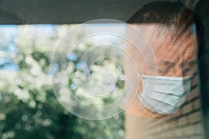 Worried man with protective face mask in self-isolation home quarantine during coronavirus outbreak