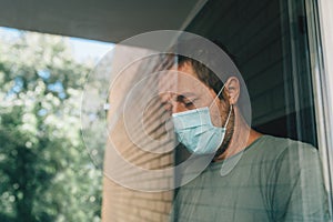 Worried man with protective face mask in self-isolation home quarantine during coronavirus outbreak