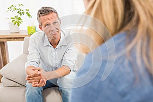 Worried man sitting on couch and talking to therapist