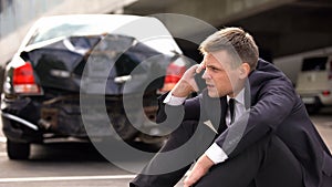 Worried man talking on phone outdoors broken auto background, traffic collision