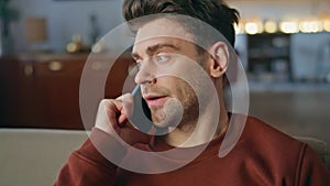 Worried man talking smartphone in apartment close up. Portrait serious guy call