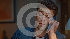 Worried man talking smartphone in dark modern apartment closeup. Frowning guy