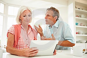 Worried Middle Aged Couple Looking At Digital Tablet