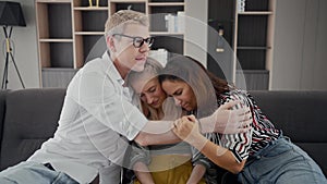 Worried mom and dad comforting depressed teen daughter bonding at home. Fam loving understanding and supporting sad teenage girl