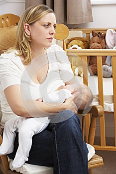 Worried Mother Breastfeeding Baby In Nursery