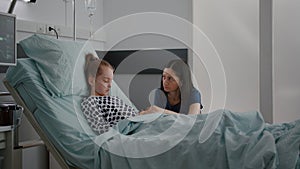 Worried mother standing with daughter praying while sleeping after recovery surgery