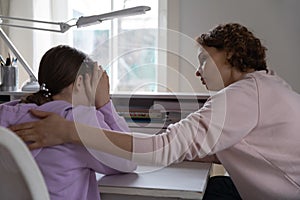 Worried mother talking comforting upset teen daughter at home