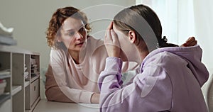 Worried mum comforting solacing upset crying teenage daughter at home