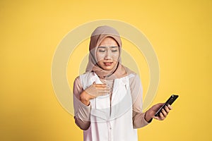 worried muslim woman in hijab using a cell phone