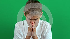 Worried nervous teenage boy sitting and thinking, begging, praying over green screen chroma key background