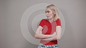 Worried nervous young woman looking aside, biting lips isolated on grey wall