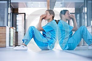 Worried nurse sitting on floor