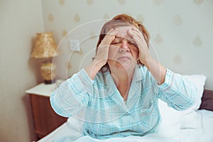 Worried old woman has headache at home.