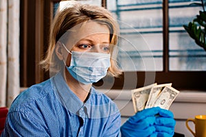 Worried person with virus protection mask and gloves holding money