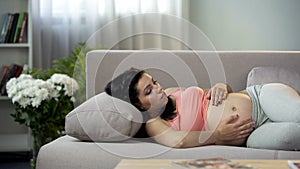 Worried pregnant woman concerned about her future baby, touching belly gently