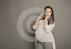 Worried pregnant woman talking on phone copy space