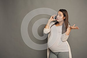 Worried pregnant woman talking on phone copy space