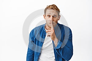 Worried redhead man asking to keep quiet, have secret, shushing with finger pressed to lips, make shhh hush sign with