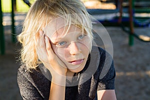 Worried, sad child alone in school playground