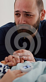 Worried sad father crying beside sick daughter waiting for healthcare treatment