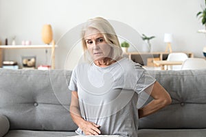 Worried sad older woman touching back feeling back pain