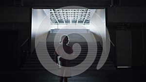 Worried schoolgirl walk down empty stairway alone. Girl enter dark corridor.