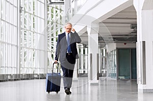 Worried senior businessman walking with travel bag