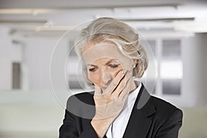 Worried senior businesswoman with hand on mouth in office