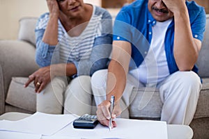 Worried senior couple checking bills in living room