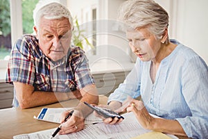 Worried senior couple checking their bills