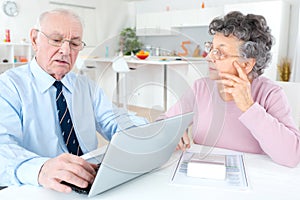 Worried senior couple using laptop at home
