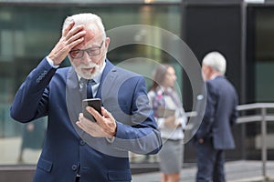 Worried senior businessman receiving bad news from business partners, holding his head photo