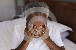 Worried senior man covering his eyes in bedroom