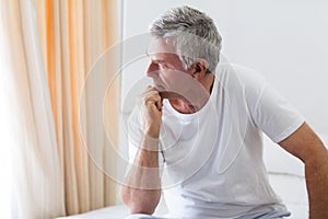 Worried senior man sitting on bed