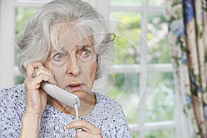 Worried Senior Woman Answering Telephone At Home photo