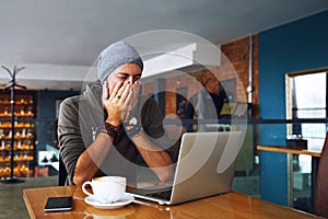 Worried shoked man with beard looking on laptop at cafe photo