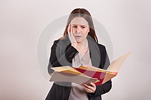 Worried stressful expression on females face holding scattered papers and folders