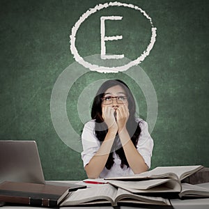 Worried student with E grades on blackboard photo