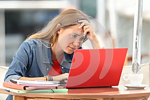 Worried student searching on line in a laptop