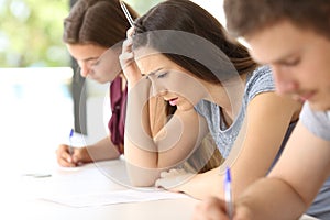 Worried student trying to do a difficult exam photo