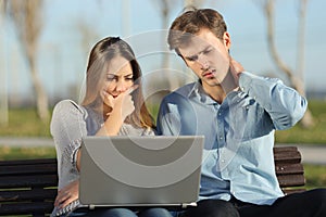 Worried students or entrepreneurs watching a laptop outdoors photo