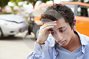 Worried Teenage Driver Sitting By Car After Traffic Accident